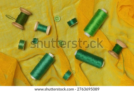 Sewing kit, green thread on spools and bobbins, buttons, top view.