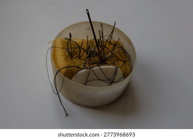 Sewing kit with needles, threads, and tools on white background. Minimal composition with handmade accessories, perfect for craft and hobby concepts.