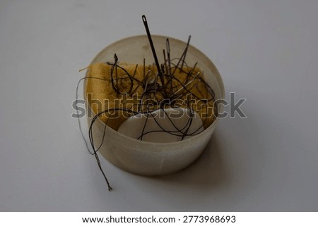 Sewing kit with needles, threads, and tools on white background. Minimal composition with handmade accessories, perfect for craft and hobby concepts.