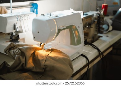 Sewing machine in action, creating clothes. The light illuminates the fabric as it's stitched together.