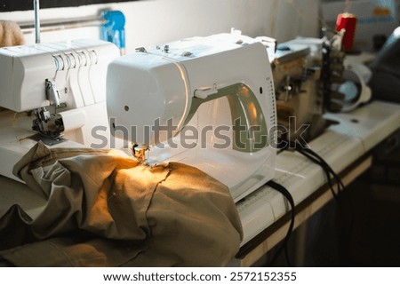 Sewing machine in action, creating clothes. The light illuminates the fabric as it's stitched together.