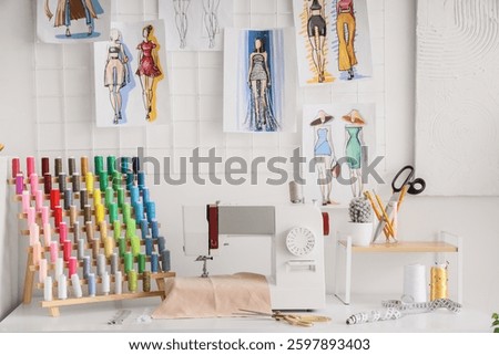 Sewing machine with cloth and thread spools on tailor's table in atelier