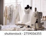 Sewing machine, fabrics, tools and patterns on table in dressmaking workshop, closeup