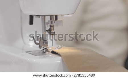 Sewing machine in focus while working on fabric in professional workshop in prof