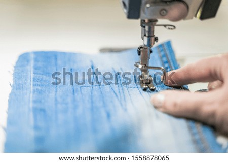 Sewing machine operator sews on a machine. Close-up depicts sewing equipment