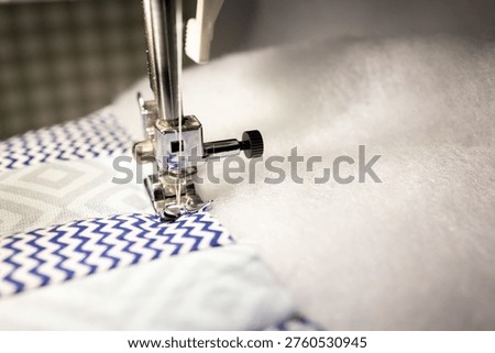 Sewing machine stitching patchwork fabric with padding polyester, quilting process close up