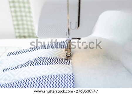 Sewing machine stitching patchwork fabric with padding polyester, quilting process close up