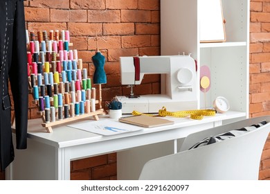 Sewing machine with thread spools and mannequin on table in atelier