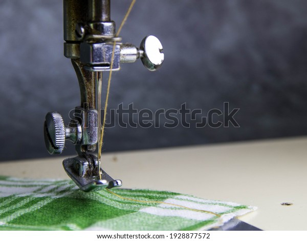 The sewing machine works with green fabric\
scotch pattern.