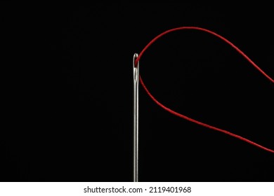 Sewing Needle With Red Thread On Black Background, Closeup