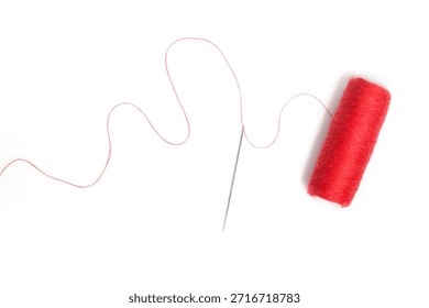 Sewing needle with red thread through the white background	