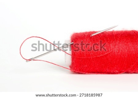 Sewing needle with red thread through the white background	