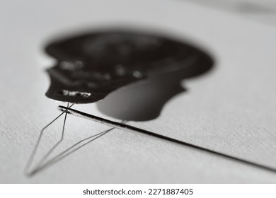 Sewing needle threader tool in use and a single black string. 