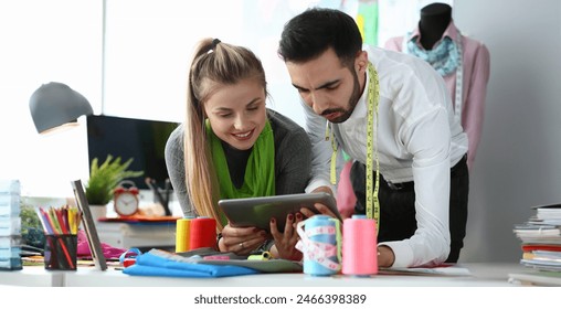 Sewing Needlework Technology Tailoring Concept. Two Professional Designers Looking in Digital Tablet in Handycraft Fashion Design Workshop. Creative Team Meeting. Couple Work on Trendy Clothes - Powered by Shutterstock