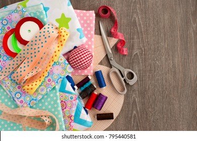 Sewing And Objects For Sewing. View From Above. Fabric, Tailoring Scissors, Centimeter Tape, Thread, Ribbon, Drawings Are Needed For Sewing Clothes. Sewing Items Are Stacked Together.