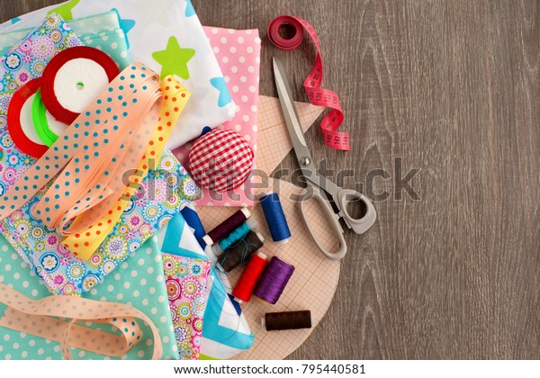 Sewing\
and objects for sewing. View from above. Fabric, tailoring\
scissors, centimeter tape, thread, ribbon, drawings are needed for\
sewing clothes. Sewing items are stacked\
together.