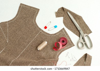 Sewing process. The process of sewing clothes on a white background. Cloth, tailoring scissors, needles, threads, centimeter tape on the table. Cut the dress according to the pattern.