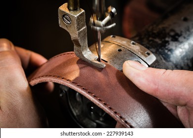 Sewing process of the leather belt. Man's hands behind sewing. Leather workshop. - Shutterstock ID 227939143