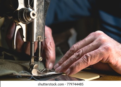 Sewing process of the leather belt. old Man's hands behind sewing. Leather workshop. textile vintage sewing industrial
