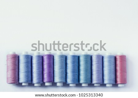 Sewing supplies and accessories for needlework. coils of blue green purple violet pink lilac thread for sewing clothes on white background.