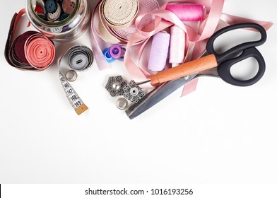 Sewing Supplies And Accessories For Needlework. Scissors, Threads, Needles, Tapes, Buttons, Tape Measure, Thimble, Seam Ripper, Fabric On White Table Background. Top View, Copy Space