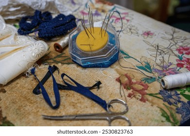 Sewing Supplies on a Floral Table with Needles, Thread, and Lace Fabric - Powered by Shutterstock