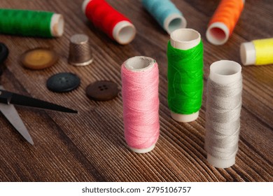 Sewing Thread Spools With Buttons And Scissors On Wooden Table