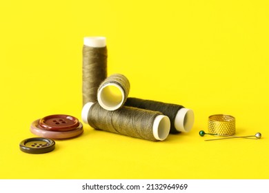 Sewing thread spools, pins, thimble and buttons on color background
