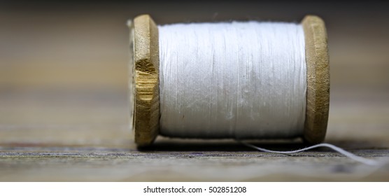 Sewing thread white needles closeup on wooden background