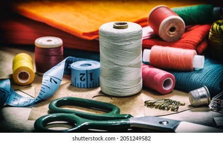 Sewing threads for sewing and various accessories for needlework. A set of sewing accessories for sewing, spools of thread, fabrics, scissors and a thimble close-up. Retro style 