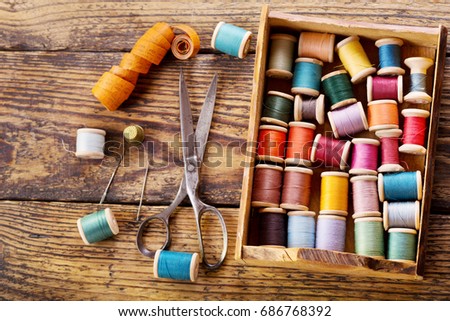sewing tools : old scissors, bobbins with thread and needles on wooden table, top view