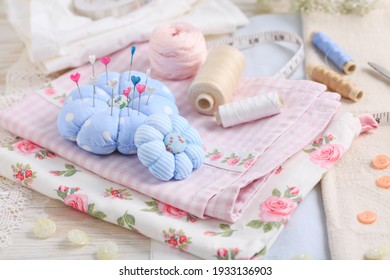 Sewing tools and supplies - handmade pincushion, scissors, bobbins with thread, needles and fabric. Hobby, crafting, creativity, free time at home concept.