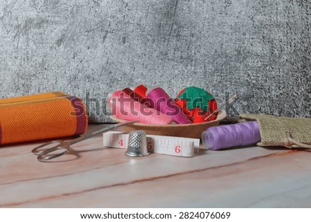 sewing tools: thimble, bobbin, needle, colored threads, tape measure