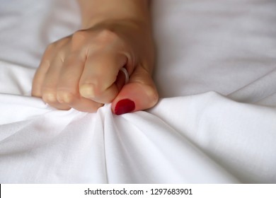 Sex Concept, Female Hand With Red Nails Pulling And Gripping White Bedsheet In Ecstasy. Orgasm Of Woman On The Bed, Feelings And Emotion