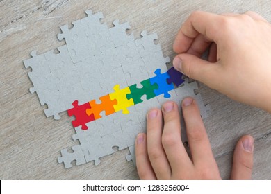 Sex Education In The Spirit Of Equality And Tolerance: A Student Builds A LGBT Pride Flag Of The Puzzle, Short Focus, Top View