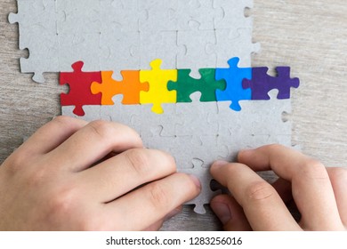 Sex Education In The Spirit Of Equality And Tolerance: A Student Builds A LGBT Pride Flag Of The Puzzle, Short Focus, Top View