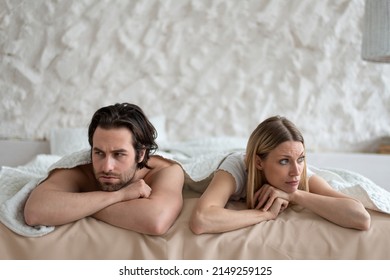 Sexual problems, relationship crisis. Stressed young couple lying in bed, overwhelmed with family difficulties, not speaking after conflict, suffering from erectile dysfunction or lack of libido
