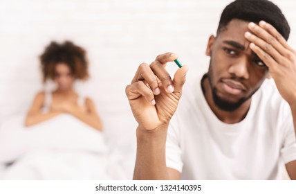 Sexuality And Impotence Problem Concept. Upset Black Guy Taking Potency Pill Before Sex With Girlfriend, Empty Space