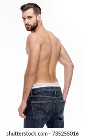 Sexy Back. Rear View Of Young Shirtless Man In Jeans Looking At Camera While Standing Against White Background.