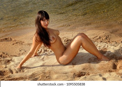 Sexy and beautiful brunette woman naked in the beach next to the river 