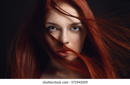 Sexy beautiful redhead girl with long hair. Perfect woman portrait on black background. Gorgeous hair and deep eyes. Natural beauty, clean skin, facial care and hair. Strong and thick hair. Flower