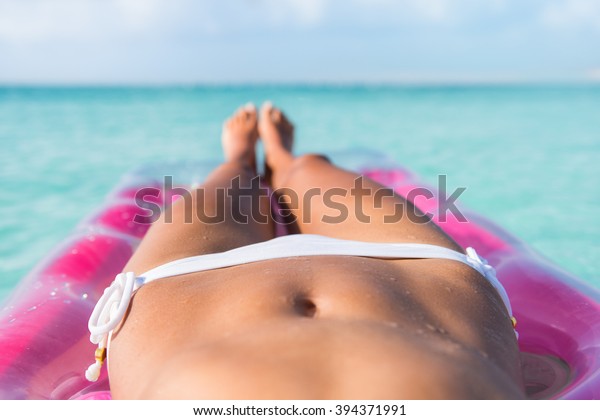 セクシーなビキニの体は胃の接写 日焼けを落とすビーチの女性の脚は カリブ海の熱帯地方の青緑海やプールの上のエアマットレスベッドでくつろいでいる の写真素材 今すぐ編集