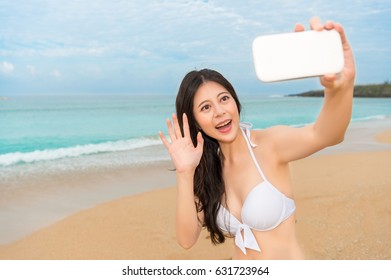 Sexy Bikini Woman On Beach Using Mobile Phone With Family Facetime And Making The Hello Gesture Taking Photo Together, And Sharing Pretty Ocean Scenery Background.