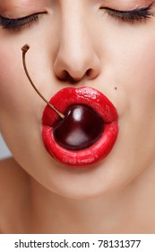 Sexy Bite! A Closeup Of A Young Pretty Women Face Holding A Yummy Cherry In Her Mouth.