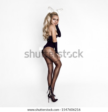 Sexy blond model dressed in  Easter bunny costume, standing on a white background and sensually posing.Halloween and Easter funny costume - Image