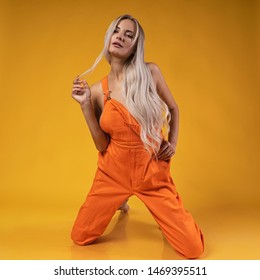 
sexy blonde girl in an orange suit on a yellow background - Shutterstock ID 1469395511