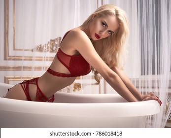 Sexy blonde girl in total red lingerie posing in modern bath looks so sexy and so excited with her red lips