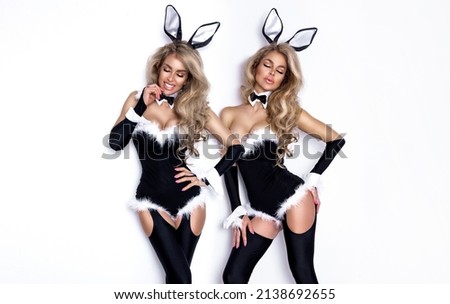 Sexy blonde model dressed in Easter bunny costume and bunny ears is standing on a white background and sensually posing. Halloween and Easter bunny costume - Image. Sexy bunny woman.