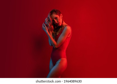 Sexy Blonde Woman Portrait Wearing Red Swimsuit Against Red Background. Color Gel Portrait.