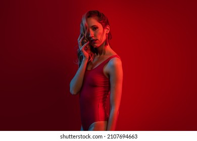 Sexy Blonde Woman Portrait Wearing Red Swimsuit Against Red Background. Color Gel Portrait.